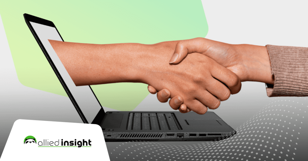 Two people shaking hands over a laptop computer.